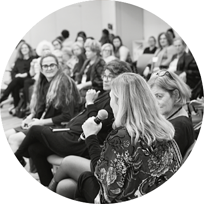 Woman holding microphone speaking to a group at a conference